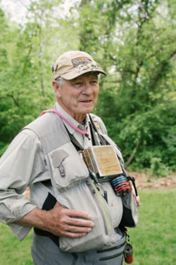 Thomas Baltz showing off his loaded fishing vest while fly-fishing.